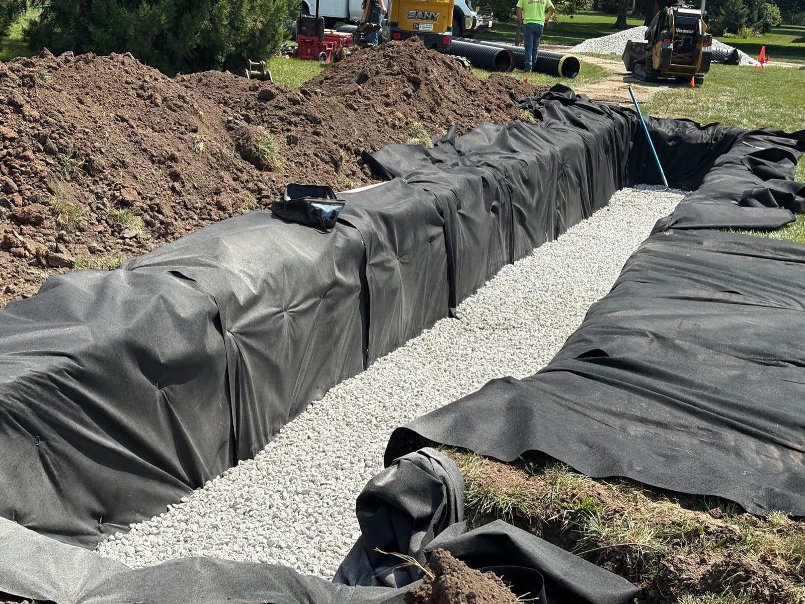 A long fabric-lined leach bed trench being backfilled with washed stone