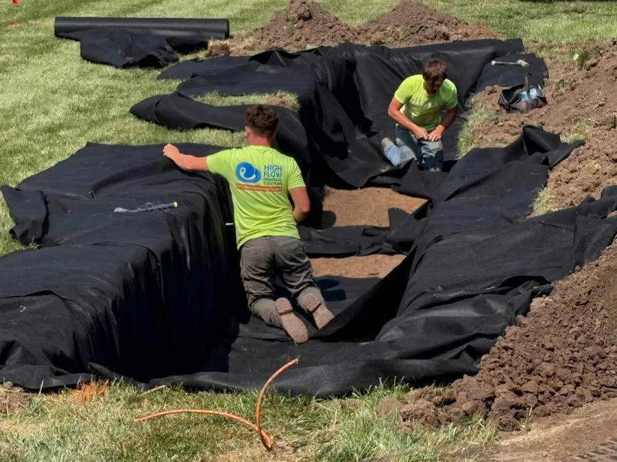 Installers laying filter fabric across the excavated leach bed before the chambers go in