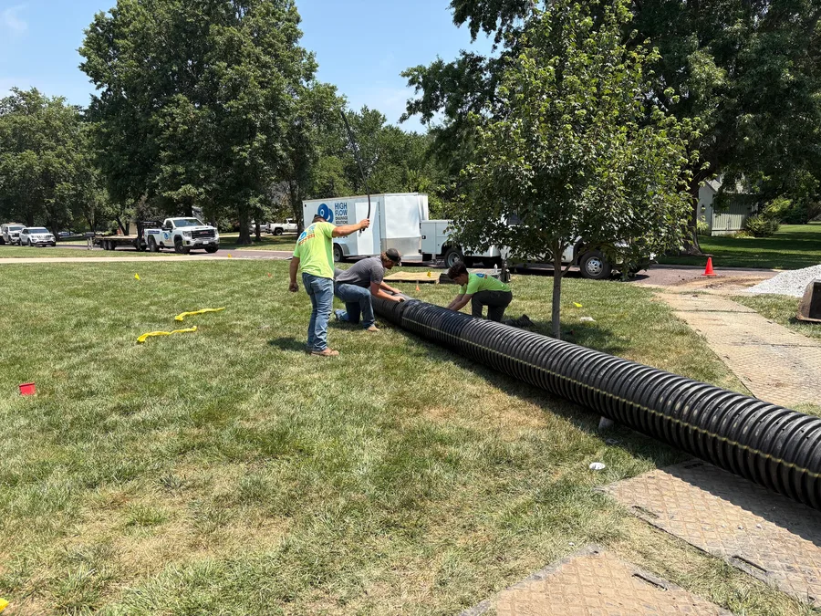 Crew joining a long run of corrugated pipe across a lawn to feed the leach bed